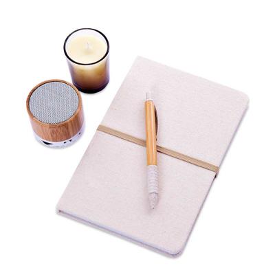Kit com caderno, caixa de som, vela e caneta