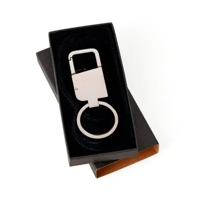 Chaveiro em Metal cromado com mosquetão. Está acomodado em uma embalagem interna aveludada. Tipo ...